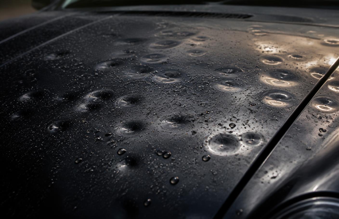 Close-up of hail dents across the hood of a dark-painted vehicle